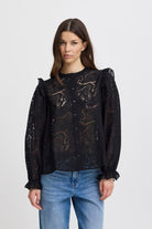 Sheer printed black button front top featuring ruffled shoulders and cuffs.