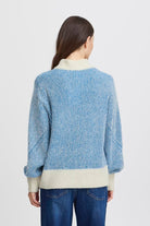 Blue sweater featuring a cream mock neck and ribbed cuffs on the sleeves and waistband.