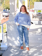 Blue sweater featuring a cream mock neck and ribbed cuffs on the sleeves and waistband.