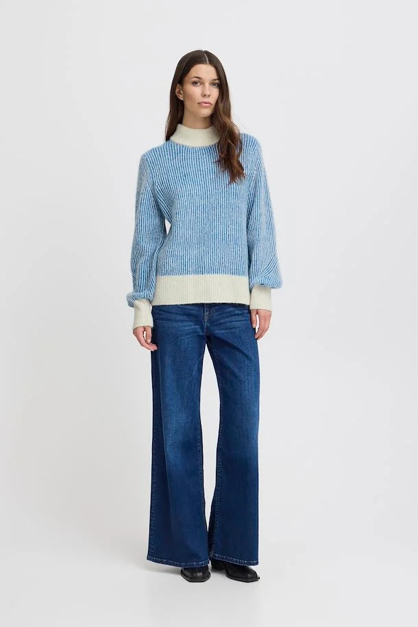 Blue sweater featuring a cream mock neck and ribbed cuffs on the sleeves and waistband.